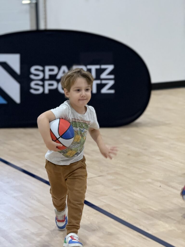 A child running with a basketball during a Spartz Sportz trial class