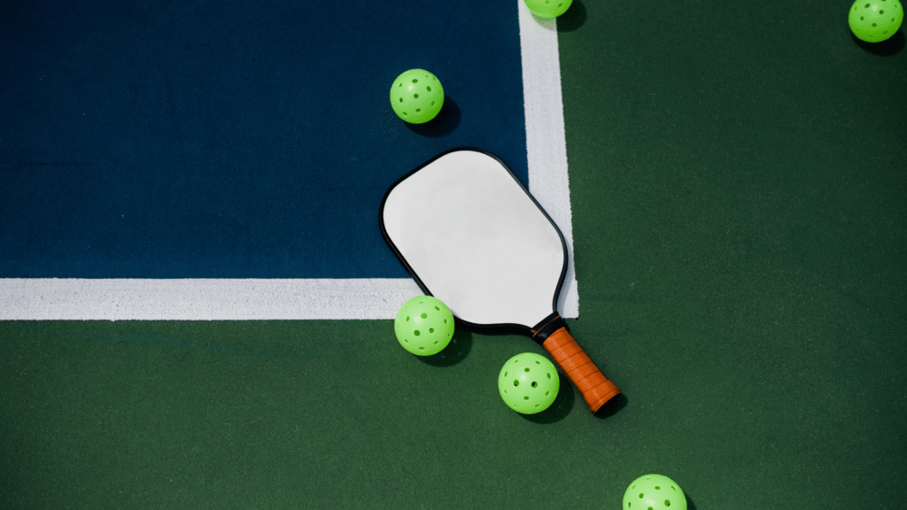 Pickleball paddle and ball resting on a premium court, ready for play.