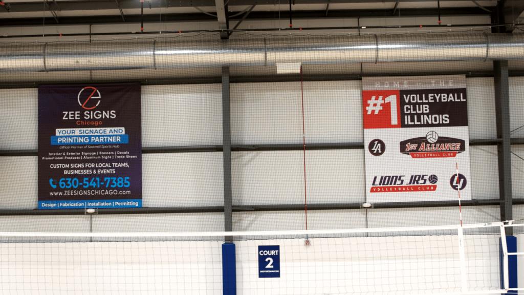 Beautifully printed large scale signs hang in Sawmill Sports Hub promoting our volleyball program and our signage partner, Zee Signs.