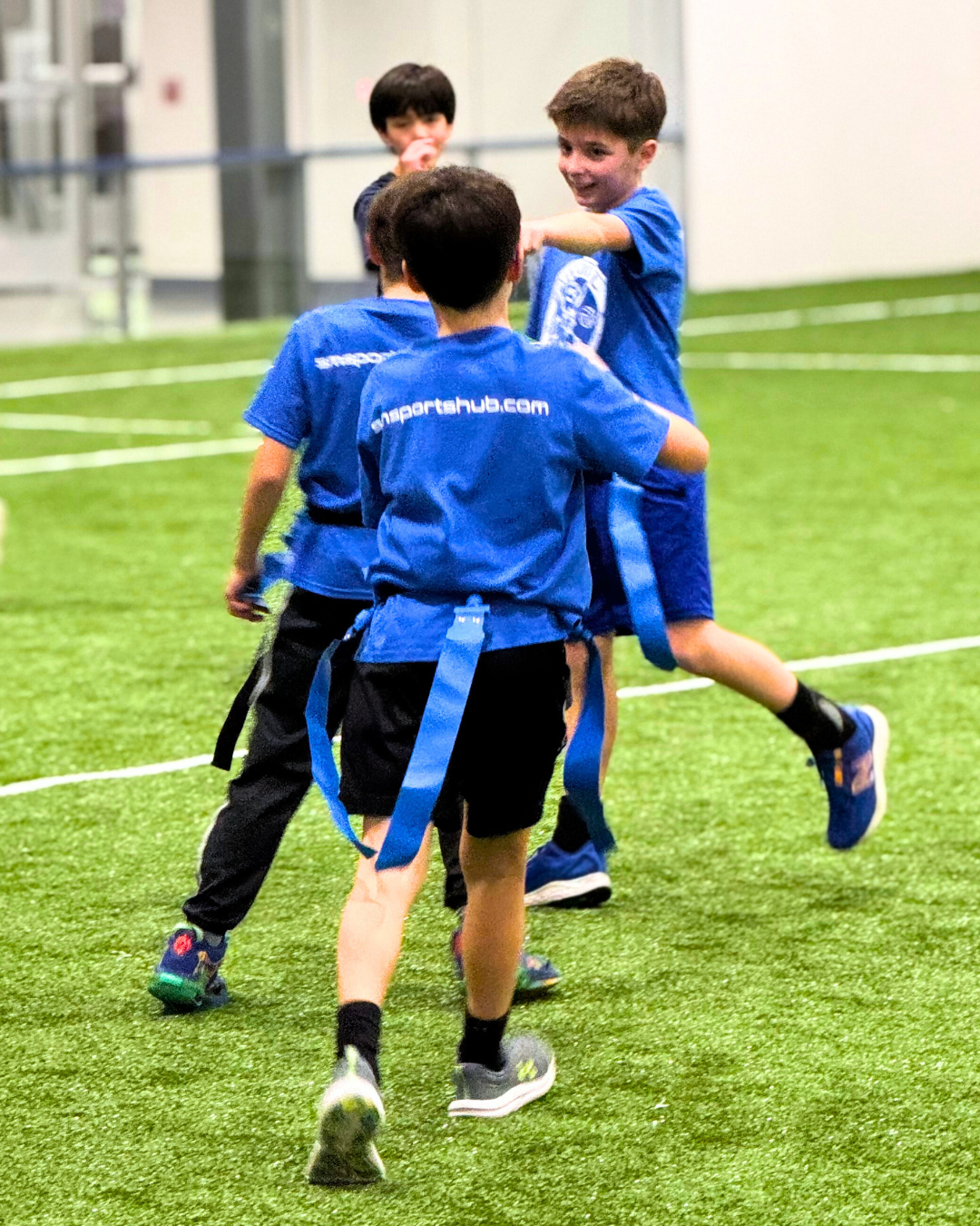 Children playing flag football indoors.
