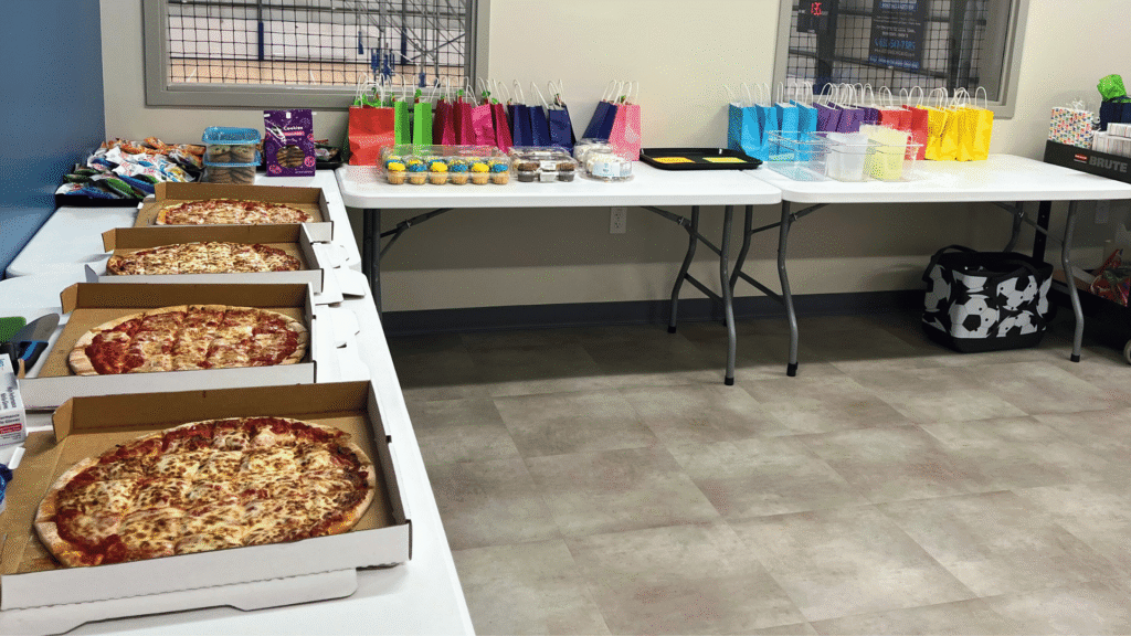 An image of a birthday party set-up with tables of pizza, cups and goodie bags or a kids sports themed birthday party.
