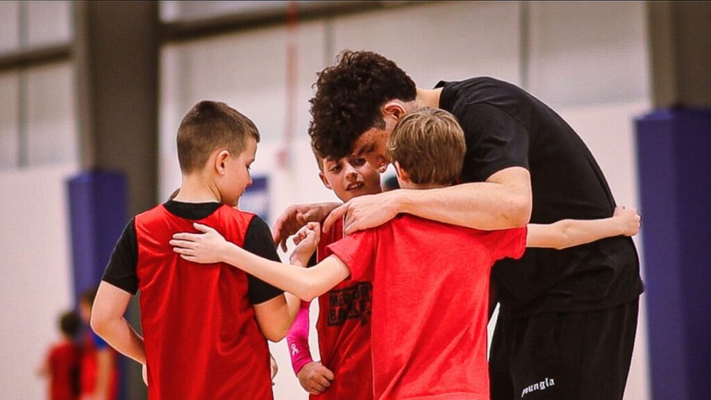 Mercury Elite youth basketball players huddle and hug at their practice.
