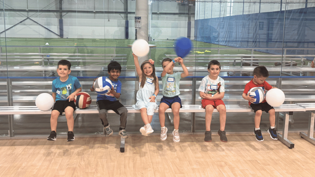 Sawmill summer camp attendees sitting on a bench holding balloons and smilnig.